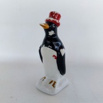 ESCULTURA - PORCELANA: Antiga escultura em porcelana representando pinguim de geladeira, modelo cartola, apresenta falhas na pintura, medida: altura:20 cm