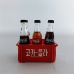 COLECIONISMO - COCA COLA: Antigo conjunto composto por um engradado de plástico rígido e quatro garrafinhas de vidro da coca cola (um esta vazia), medidas: altura:8 cm, largura:6 cm e comprimento:8 cm