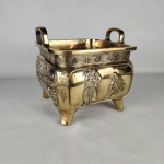 FFF010 Cachepot em bronze de inspiração oriental com forma quadrada e quatro pés. Apresenta alças la