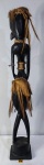 ARTE AFRICANA - Grande escultura étnica de origem africana, possivelmente iorubá, em monobloco de madeira nobre com adornos em sisal natural representando figura humana. Medidas: 100 x 16 x 15 cm.