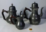 Conjunto de leiteira e dois buless em estanho da marca "Faemam", alças em madeira. Alt da bule maior: 24 cm. OBE: apresentam marcas do tempo.