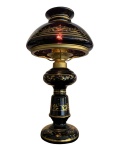 Antigo abajur de vidro na cor violeta escuro com estrutura de metal, decorado com folhas de acanto e faixas pintadas de dourado. Fiação original. Funcionando. Dimensões: 36 cm.