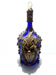 Garrafa de 5L de  vidro na cor azul decorado com rosto, detalhes vegetalistas e pedras semipreciosas. Dimensões: 45 cm.