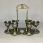 Antigo Conjunto com seis cálices em metal cinzelado com suporte. Marcas de desgastes. Dimensões:  suporte: 19 cm x 25 cm / cálices: 6 cm x 5 cm.