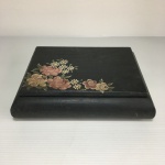 Caixa de madeira retangular. Patinada de preto, decorada com arranjos florais pintados à mão. Dimensões: 5 cm x 14 cm x 19 cm.