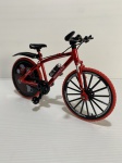 Miniatura de bicicleta na cor vermelho e preto com ricos detalhes. Peças feitas de metal, borracha e plástico. Dimensões: 19 cm comprimento.