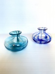 Dois pequenos vasos de pasta de vidro translúcido com faixas azul. Dimensões: 6 cm x 8 cm (cada).