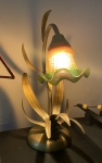 Antiga luminária de mesa de metal, revestido de dourado, decorada com folhagens com cúpula de vidro na cor laranja e verde. Funcionando. Dimensões: 40 cm altura.