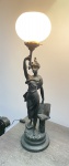 Antiga luminária de metal ostentando figura feminina. Cúpula de vidro. Fiação funcionando. Dimensões: 70 cm.