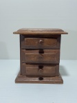 Miniatura de cômoda de madeira com três gavetas. Dimensões: 10,5 cm x 10 cm x 5,5 cm.