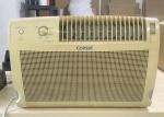 Ar -condicionado da marca Consul, modelo 7500 classe A. Está funcionando e gelando. Apresenta marcas de uso. Grade traseira de proteção faltando partes.