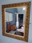 Grande e pesado espelho com grossa moldura em madeira ricamente entalhada com pintura em folhas de ouro -med. 142x104cm.