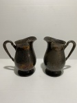Lote com duas jarras em metal cinzelado, banhado à prata. Dimensões: 24 cm (cada peça).