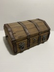 Baú de madeira com tiras de couro e detalhes com busto de leão. Interior em tecido vermelho. Tampa solta, necessitando de reparo.  Dimensões: 15 cm x 20 cm x 35 cm aproximadamente.