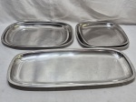 Baixela com 5 peças em aço inox Meridional. Composto de 3 travessas retangulares e 2 travessas quadradas. Medindo a maior 52,5cm x 22cm.