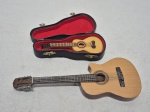 Lote de 2 miniaturas de violão e cavaquinho em madeira. Medindo o maior 21cm de comprimento.