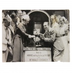 Minnie waiting for her pal Mickey  - Walt Disney, 1935. Walt Disney posa com estudantes e enfermeiros na inauguração do marco de arrecadação de fundos para a reconstrução do hospital de Westminster, no Reino Unido. Na imagem Disney ausculta uma Minnie de pelúcia com um estetoscópio, auxiliado por uma enfermeira, sob a legenda: `Por favor jogue seus trocados aqui. Aqui está Minnie esperando por seu parceiro Mickey e o Sr. Walt Disney`. Na semana seguinte o então Príncipe de Gales Eduardo VIII colocou a pedra fundamental do novo edifício, uma tradição na qual a primeira pedra da construção é simbolicamente posicionada para dar início às obras. Texto no verso: `WALT DISNEY TESTS MINNIE’S HEART! INAUGURATES WESTMINST HOSPITAL REBUILDING FUND. Walt Disney, creator of Mickey Mouse, inaugurated Westminster Hospital’s rebuilding scheme fund. The foundation stone of the new building is to be laid this week by the Prince of Wales. PHOTO SHOWS: Walt Disney testing the heart of Minnie Mouse with a stethoscope watched by students and nurses. Clem - June 24th 1935 PN.r.` A foto procede de um arquivo italiano.
