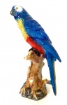 Grande figura de arara em cerâmica policromada de múltiplas cores, arara repousada sobre tronco. Alt