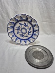 Lote de 2 pratos decorativos, sendo um em porcelana e um em estanho. Medindo o maior 29,5cm de diâmetro.