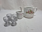 Lote de bule e leiteira em porcelana, 4 porta ovos em metal. Medindo o bule 12cm de altura.