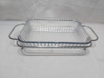 Travessa retangular em vidro temperado com suporte em aço inox. Medindo a travessa 30cm x 23cm x 5,5cm de altura.