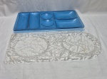 Lote de 2 petisqueiras em acrílico, sendo uma incolor e uma azul. Medindo a maior 41cm x 24cm.