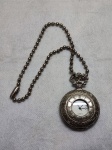 Relógio de bolso prateado com lindos detalhes na sua parte traseira, e nº romanos na parte da frente, não testado