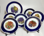 Conjunto de prato de bolo e seis pratos de sobremesa em porcelana, provavelmente europeia., bordas azuis com linda decoração de frutas ao centro de cada prato. Medidas: Prato para bolo 26 cm / pratos para sobremesa 19 cm