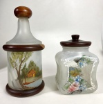 Dois potes de vidro pintados com tampa em madeira. Medidas: 17 e 25 cm de alt.