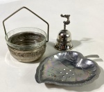 Três peças, sendo sino, pote com alça e vidro interno em metal prateado e saboneteira em inox na forma de folha. Medidas: Sina 10 cm / saboneteira 15 x 11 cm e pote 12 cm de alt. x 9 cm