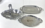 Três peças em inox sendo um cesto e duas bandejas uma com gravação Associação Antonina. Medidas do cesto 22 x 22 x 33 cm / bandeja 43 x 26 cm / 38 x 23 cm