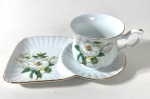 Linda xícara de chá de coleção com seu respectivo pires em porcelana nacional branca com decoração floral.