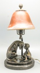 ABAJUR - Lindo abajur de mesa, para 1 luz, em bronze representando "Criança com cão". Apresenta assinatura M. GOLZE. Base em mármore. Cúpula em pasta de vidro fosco na cor rosa. Med. 36x14x18 cm.