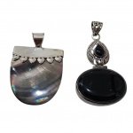 Dois pedantifes castroados em prata ambos contrastados 925, um com madrepérola e outro com ônix, 8 x 4 e 5 x 4 cm. 48, 4 g. bruto,