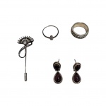 Quatro peças em prata sendo um prendedor de prata para lenços ou echarpes com pedras brilhantes, 1anel com pedras brilhantes, aro 26,  1 anel maciço chimarrão e repuxado, aro 21 e par de brincos com pedra rubilita, 20,8 g. bruto.