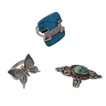 Três anéis femininos em prata, um deles contrastado, um representando libélula articulada, aro 22, um com turquesa e cascalhos de brilhantes, aro 25 e um com turquesa, 19, 29,4 g.