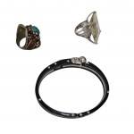 Pulseira em metal e acrílico preto e dois anéis um em metal prateado com grande quartzo de Rutilo retangular, aro 19 e outro em metal dourado com turquesa e pedra cor grená, aro 24.