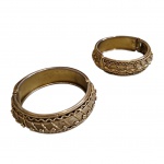 Duas pulseiras indianas douradas, lavradas e repuxadas com desenhos simétricos em alto relevo, fecham por pressão,  Diam. 6,5 cm.