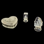 Três peças em vidro sendo  uma escultura representando anjo protegendo crianças e outro Sagrado Coração de Jesus e um porta-joias em formato de coração com bordas serrilhadas, Alt. 9 e 7 cm. e 9 x 10, Alt. 5 cm.