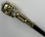 Bengala com castão no feitio de caveira em metal ouro velho. Altura: 92,5cm. Possui lâmina interna, 31cm.