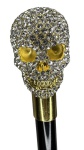Bengala com castão no feitio de caveira em metal dourado incrustado por cristais brancos. Altura: 91,5cm. Possui lâmina interna, 30cm.