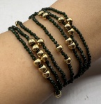 Pulseira feita com sete voltas de zircônias verdes facetadas, bolinhas e fecho em metal dourado. Comprimento aberto: 17,5cm