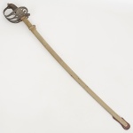 MILITARIA, uma (1) antiga espada, lâmina em aço com brasão de Armas da República, sinais de uso e oxidação, empunhadura recoberta em couro e aramado, pomo e guarda mão em bronze, bainha em metal prateado, medindo aproximadamente 92 cm comprimento, vide foto.