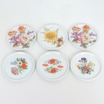 PORCELANA, seis (6) porta copos ornados com flores em policromia, manufatura SCHMIDT (Pomerode, SC; Mauá, SP; Campo Largo, PR, fundada em 1945, ainda em atividade, maior fábrica de porcelana da América Latina), medindo 8,5 cm diâmetro, sinais de uso, vide foto.