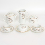 PORCELANA, conjunto tete a tete para chá com seis (6) itens: 1 bule; 1 cremeira; 1 açucareiro; 1 manteigueira e 2 xícaras, uma delas com bicado no pires, ornados com rosas em tons de cinza sobre fundo branco, arremates a ouro, manufatura RENNER (Porto Alegre, RS, fundada em 1942; em 1998 foi vendida para a Vista Alegre de Portugal; em 1999 mudou a razão social para Vista Alegre do Brasil), modelo MEDAILLON, medindo a maior peça 17,5 cm altura, sinais de uso, vide foto.