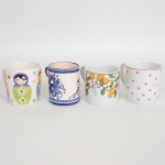 PORCELANA E FAIANÇA, quatro (4) canecas distintas: 1 com ornamentação em flores e frutas, policromada, marca EMA (marca registrada no INPE em 1999 e renovada em 2002 pela Porcelana Vista Alegre do Brasil Ltda., em atividade desde 1998 quando adquiriu a RENNER, ligada ao Grupo Vista Alegre Portugal); 1 sem marca de manufatura aparente ornada com bonecas russas em policromia; 1 ornada em poás na tonalidade rosa sobre fundo branco e legenda em inglês, marca GERMER (fundada em 1950 em Timbó, SC, como fabricante de acessórios para maquinário têxtil; em 1964 passou a produzir componentes para lançadeiras; em 1969 passou a produzir isoladores elétricos; em 1978 quando assumiu o controle da POLOVI Campo Largo, PR passou a produzir porcelana de mesa; em 1988 modernizou a fabrica com a aquisição de novos fornos, atualmente é a segunda maior produtora de porcelana do Brasil); 1 com ornamentação floral pintada a mão na técnica blue and white, todas com sinais de uso, vide foto.