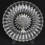 CRISTAL, uma (1) travessa ou prato para torta ou bolo, circular, grossa, incolor e translúcida, modelagem em dália e folhas, medindo30 cm diâmetro, sinais de uso, vide foto.