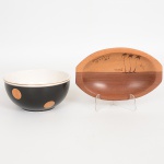 DIVERSOS, dois (2) itens: 1 tigela em louça ou faiança, ornada na tonalidade preta com poás a ouro, sobre fundo na tonalidade branca, sem marca de manufatura aparente, medindo 15,5 cm diâmetro e 7,5 cm altura, arremates da borda com frisos a ouro; 1 petisqueira entalhada em madeira, souvenir de Porto Segura, BA, medindo 19,5 x 12,5 cm, ambos com sinais de uso, vide foto.