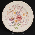 FAIANÇA, um (1) prato raso com ornamentação floral policromada, borda relevada em volutas na própria pasta, bicado visto pela parte de traz, marca VERNON KILNS, Califórnia, Made in USA (tradição desde 1931), modelo CHINTZ, medindo 26,5 cm diâmetro, sinais de uso, vide foto.