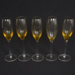 VIDRO, cinco (5) flutes de pé alto para champanhe ou espumante, bojo na tonalidade amarela em degrade, fuste quase cilíndrico e base em bolacha, ambos incolores, translúcidos, medindo 24 cm altura, sinais de uso, vide foto.